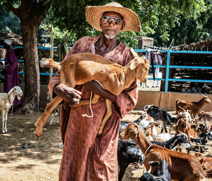 Herder in Niger with a goat in his arms.