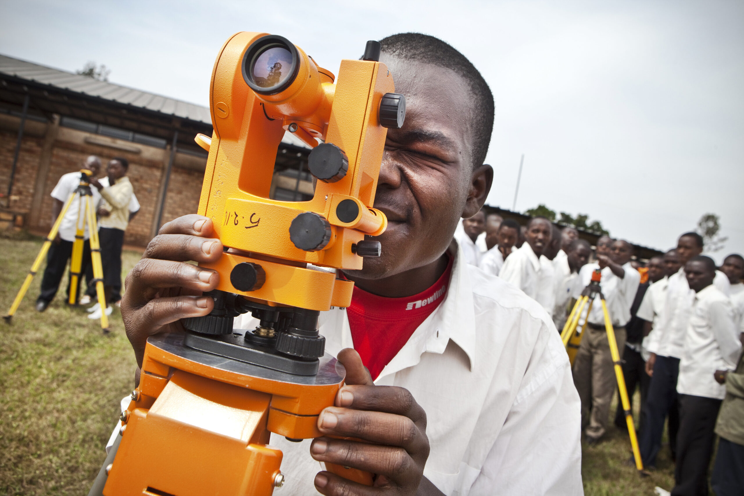 Surveyor's apprentice in Burundi looks into a surveying machine
