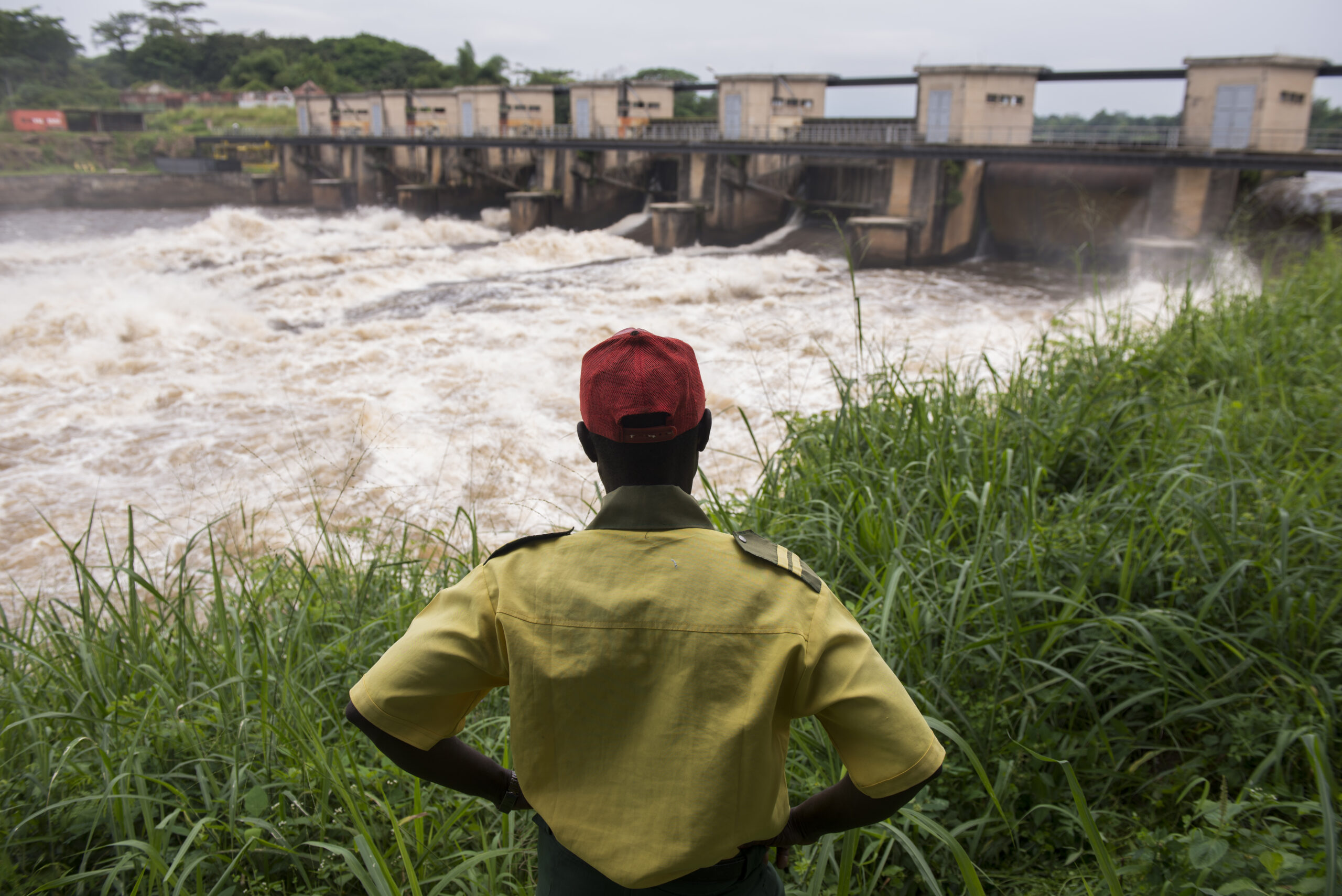 Man looking at a river and a bridge that is build nearby in Thsopo, DRC.