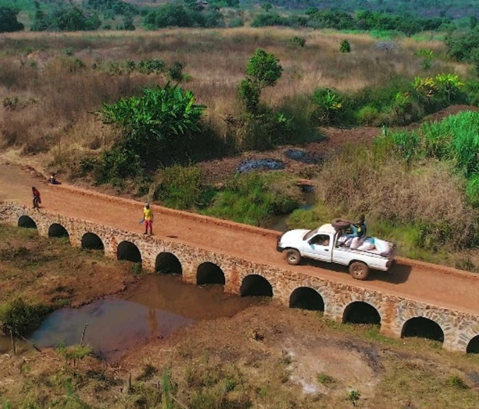 Car crossing a stone arch bridge in Tanzania.