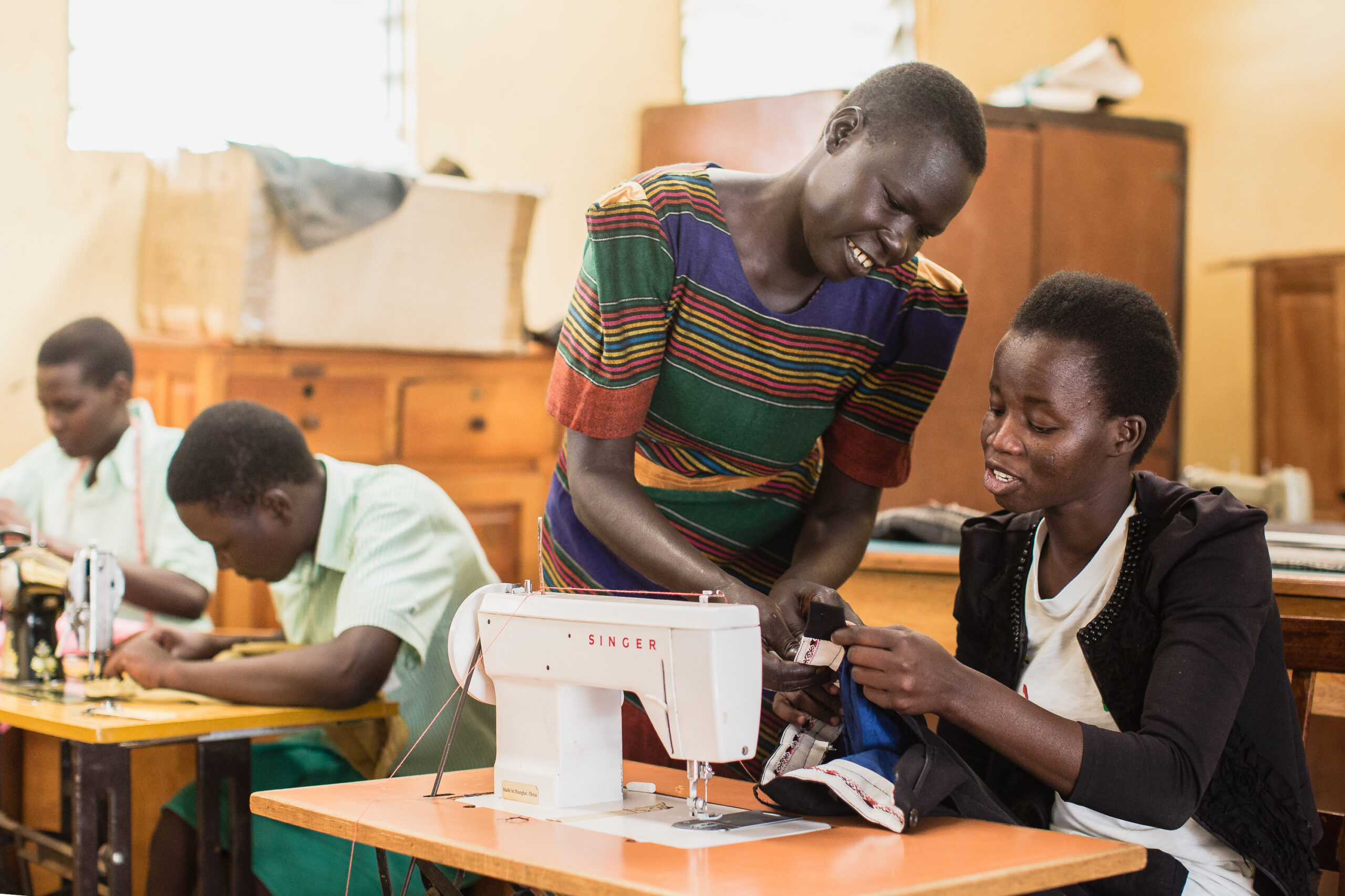 Women teacher in Uganda explaining a student how to use a sewing machine.
