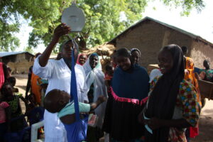 Gezondheidswerker in een dorp in Niger meet het gewicht van een kind.
