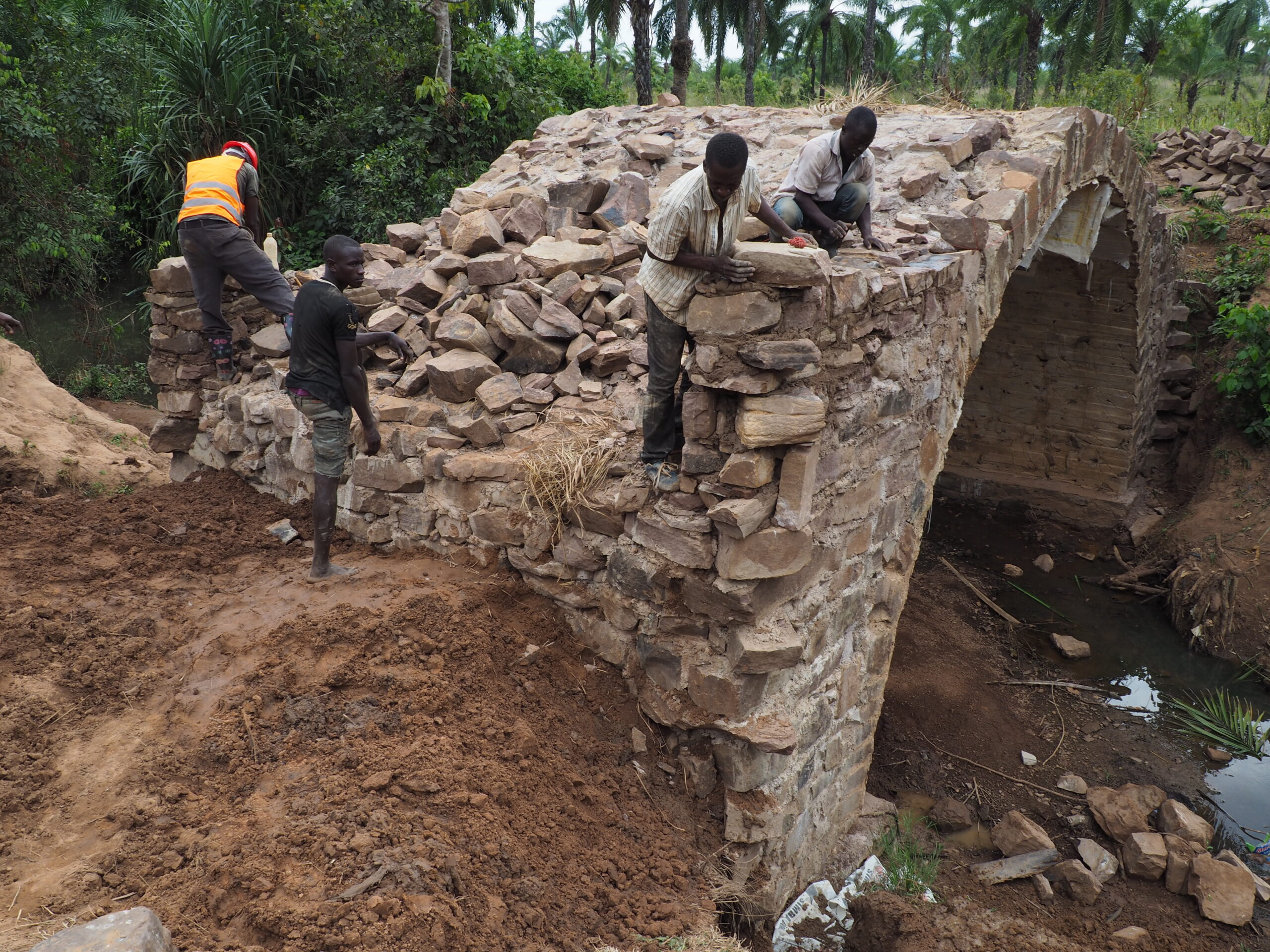 men constructing a stone arch bridge in Tanzania.