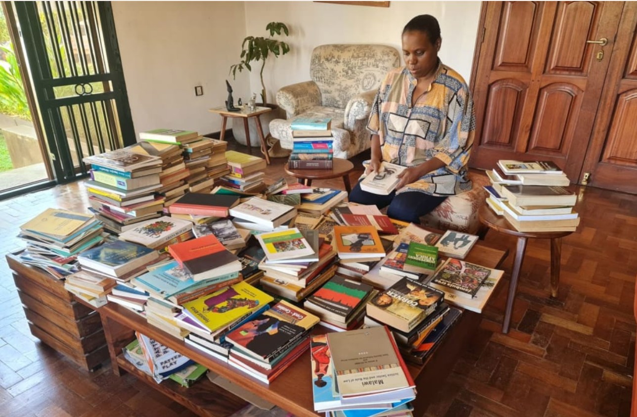 Woman reading at a table, surrounded by books.