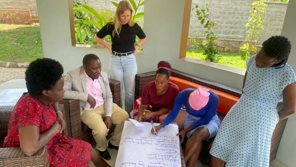 Group of people sitting around a large piece of paper.