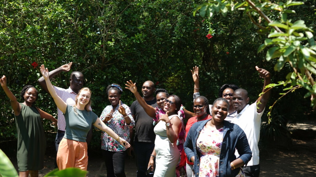 Group of people pose for a picture throwing their arms in the air.