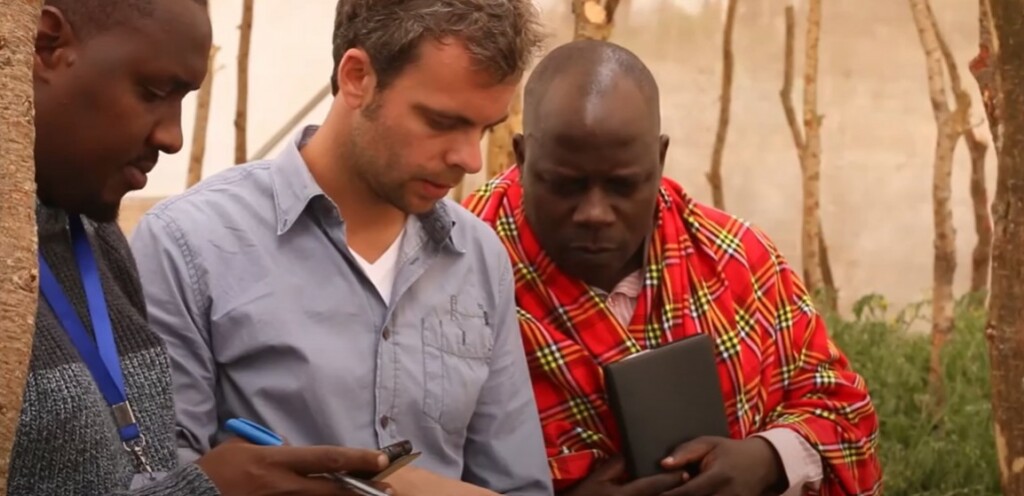Three men looking at a tablet.