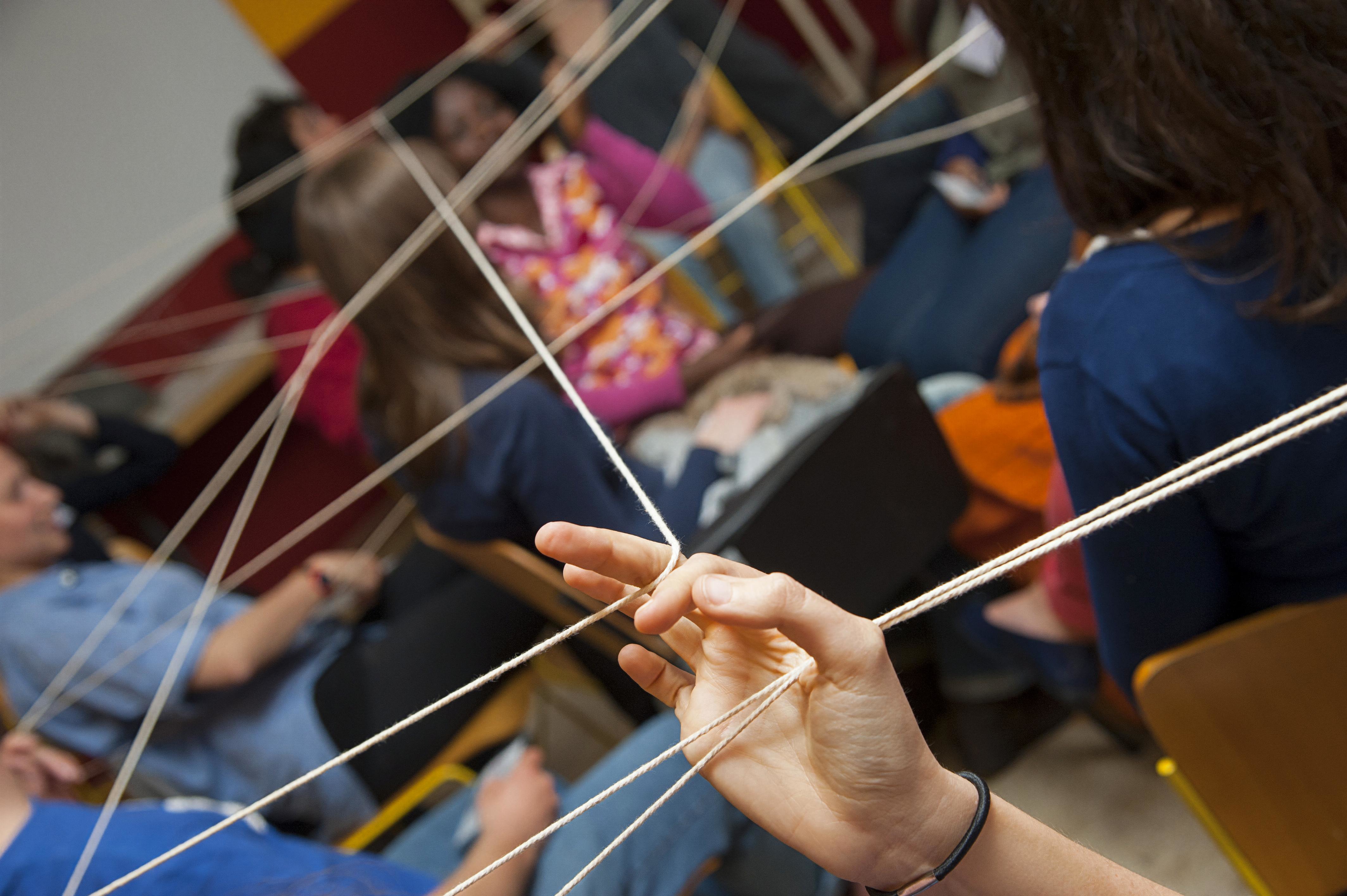 A hand holding up a string of rope.