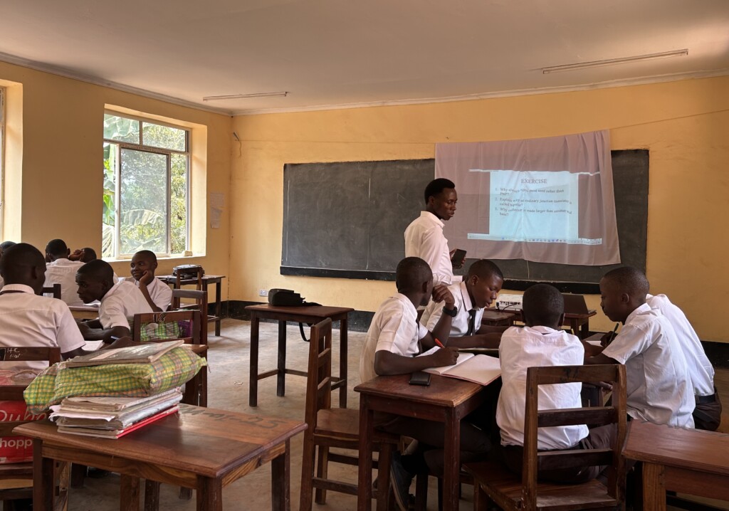 Teacher in Tanzania using a projector in classroom.