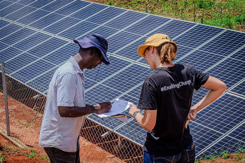two people standing next to solar mini grid