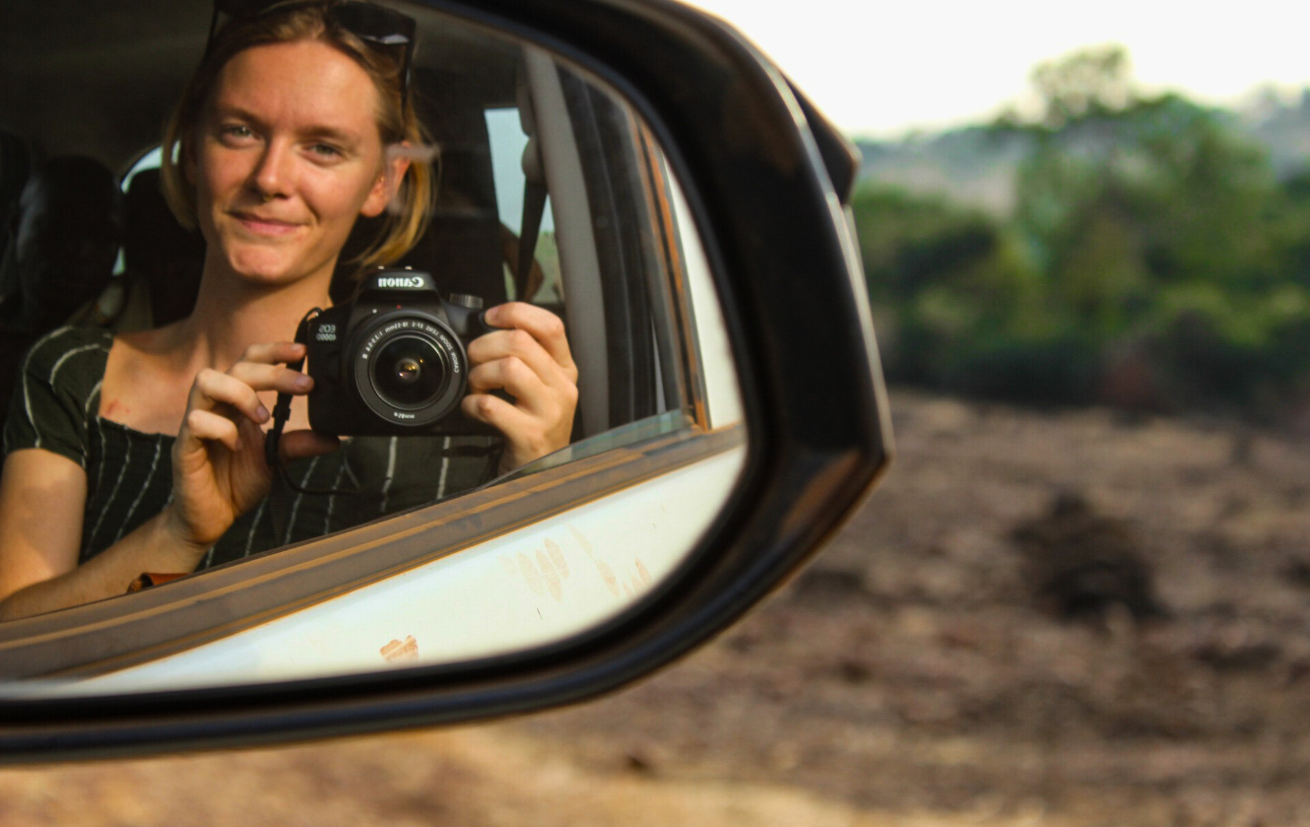 Picture of women looking into review mirror of a car