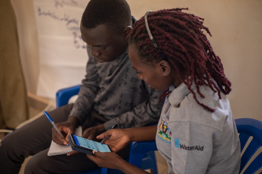 man taking notes while woman uses tap & track mobile application