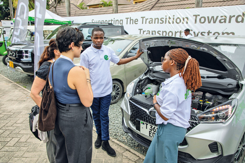 three women and a man standing next to an electric vehicle in Dar es Salaam