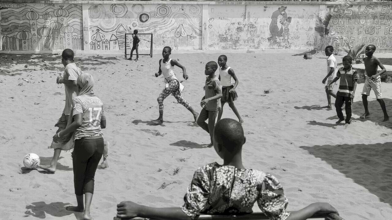 Group of children playing on a sandy football field.