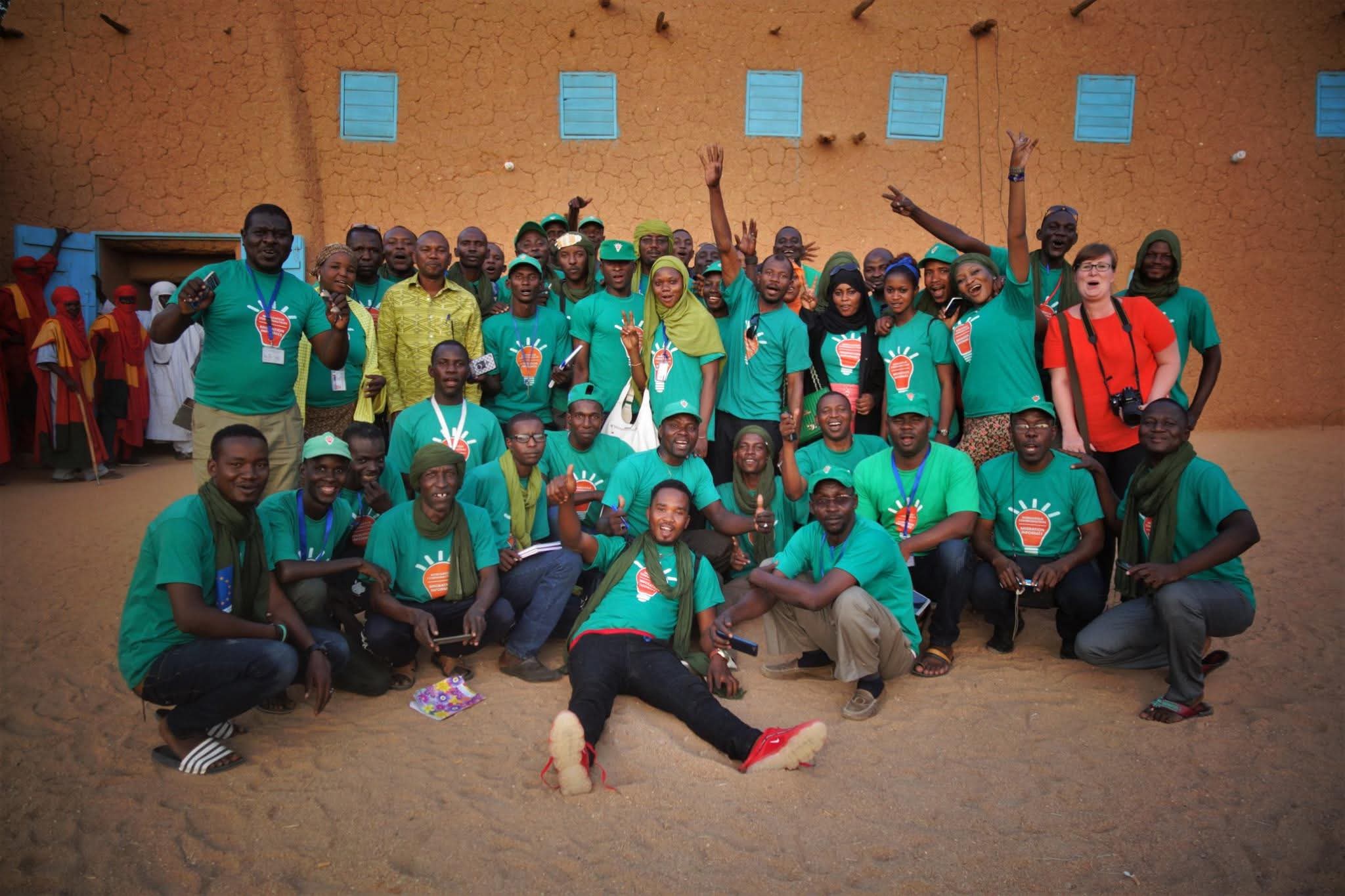 Big group of young people pose for a group picture while smiling.