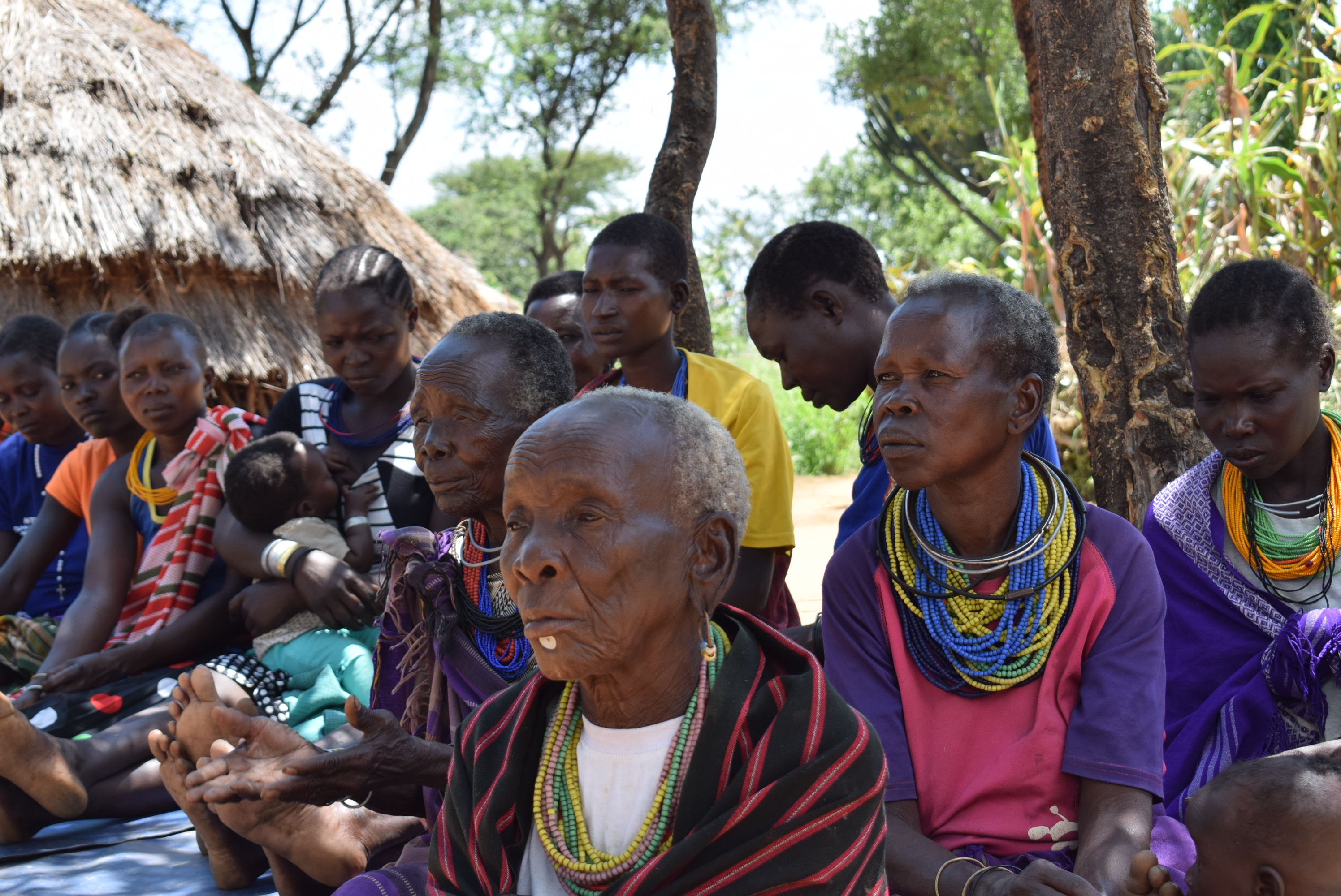 A group of 15 women in Karamoja, northern Uganda sitting together outside.