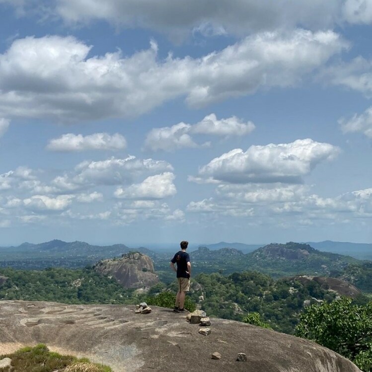 Man standing on top of rocks looking over nature via a viewpoint.